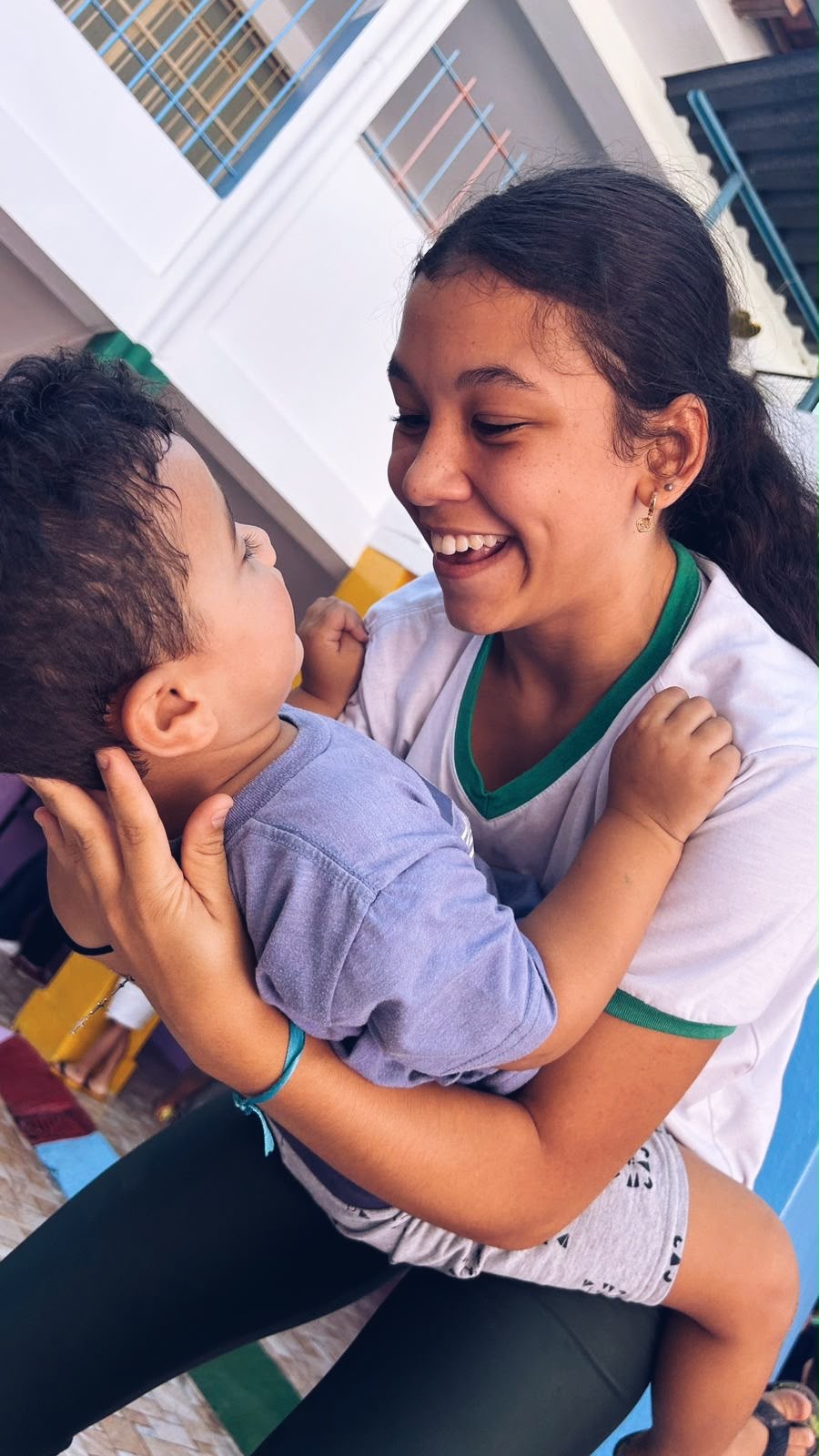 Voluntária sorrindo enquanto brinca com uma criança pequena