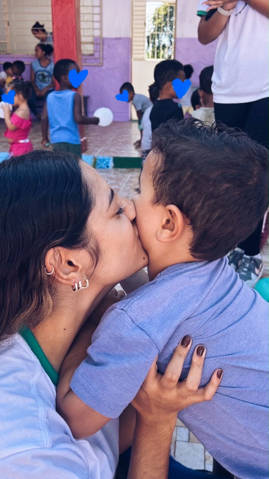 Voluntária beijando o rosto de uma criança em atividade do projeto
